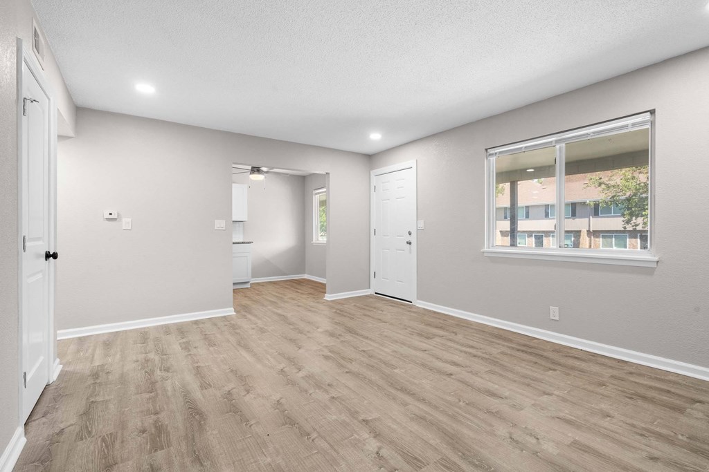 A room with light grey walls and a window with a view of a building outside.