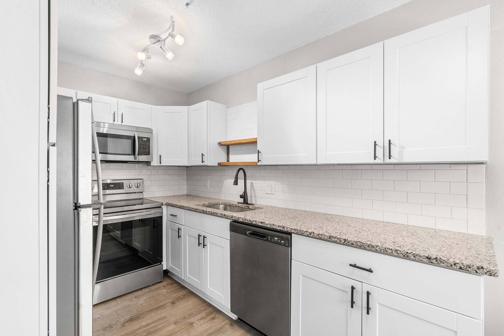 A kitchen with white cabinets and a granite countertop.