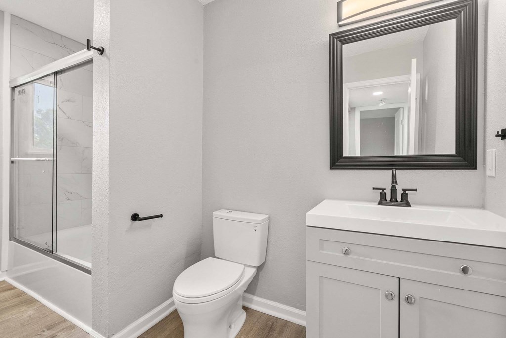 A white bathroom with a toilet, sink, and mirror.