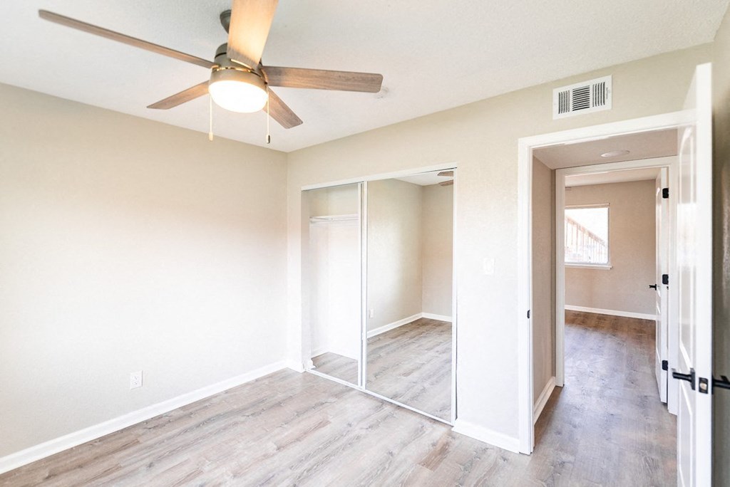 A room with a ceiling fan and sliding doors.