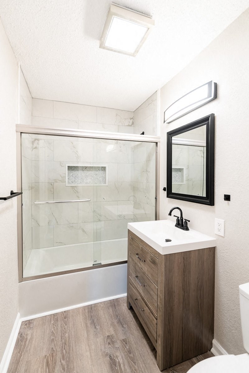 A bathroom with a sink, mirror, and walk-in shower.