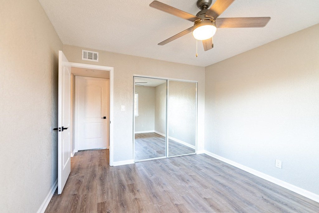 A room with a ceiling fan and wooden flooring.
