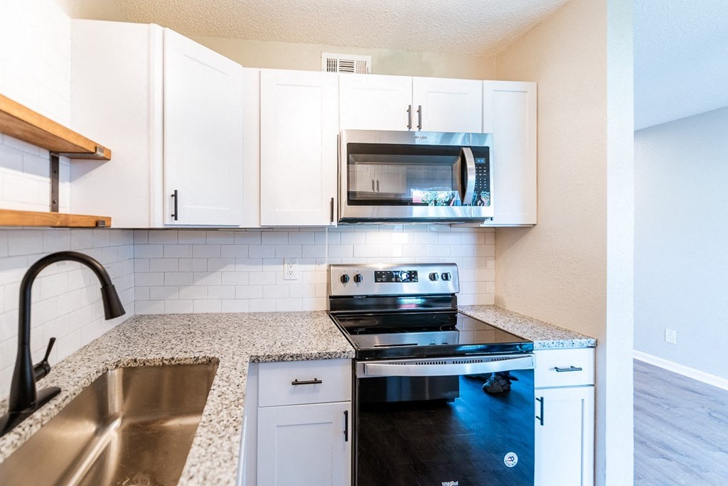 A kitchen with a stove, oven, microwave, and sink.