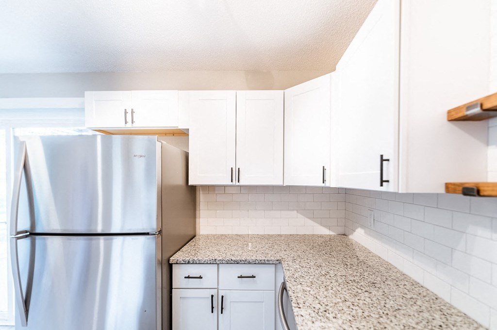 A kitchen with a refrigerator, cabinets, and a washing machine.
