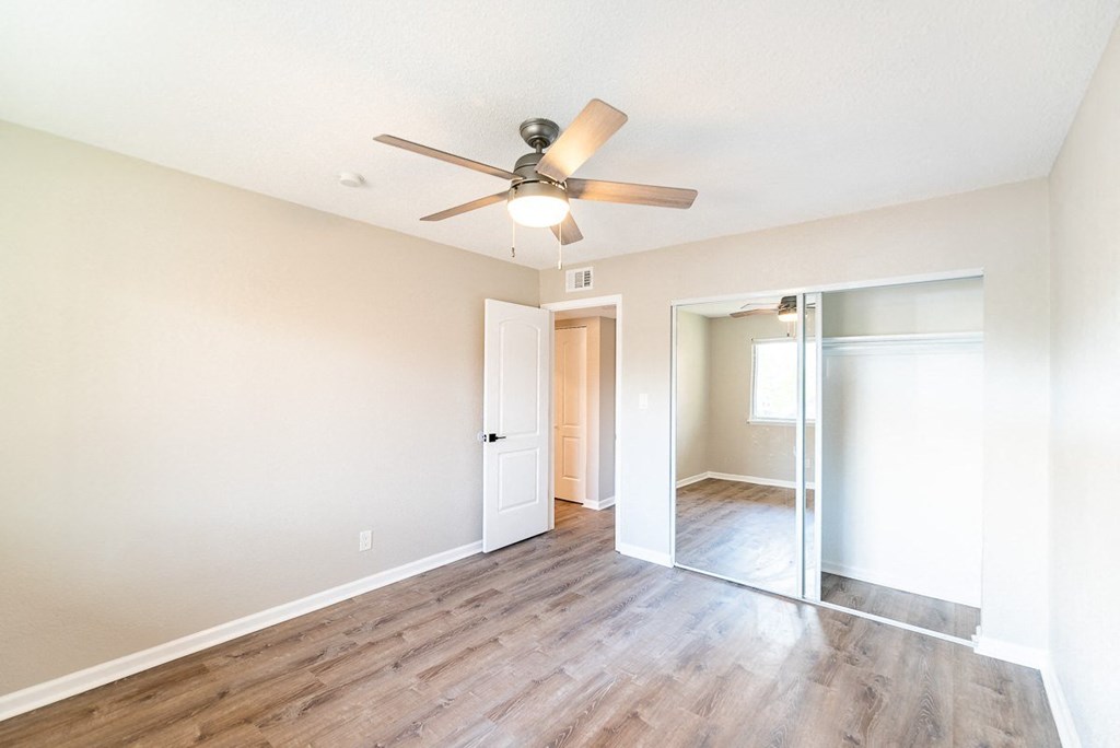 A room with a ceiling fan and wooden flooring.