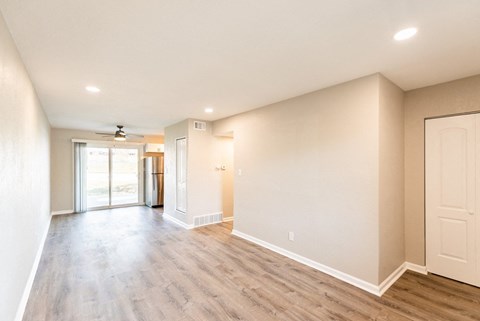 A spacious room with wood flooring and a ceiling fan.