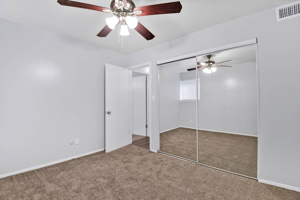 carpeted room with large closet and ceiling fan