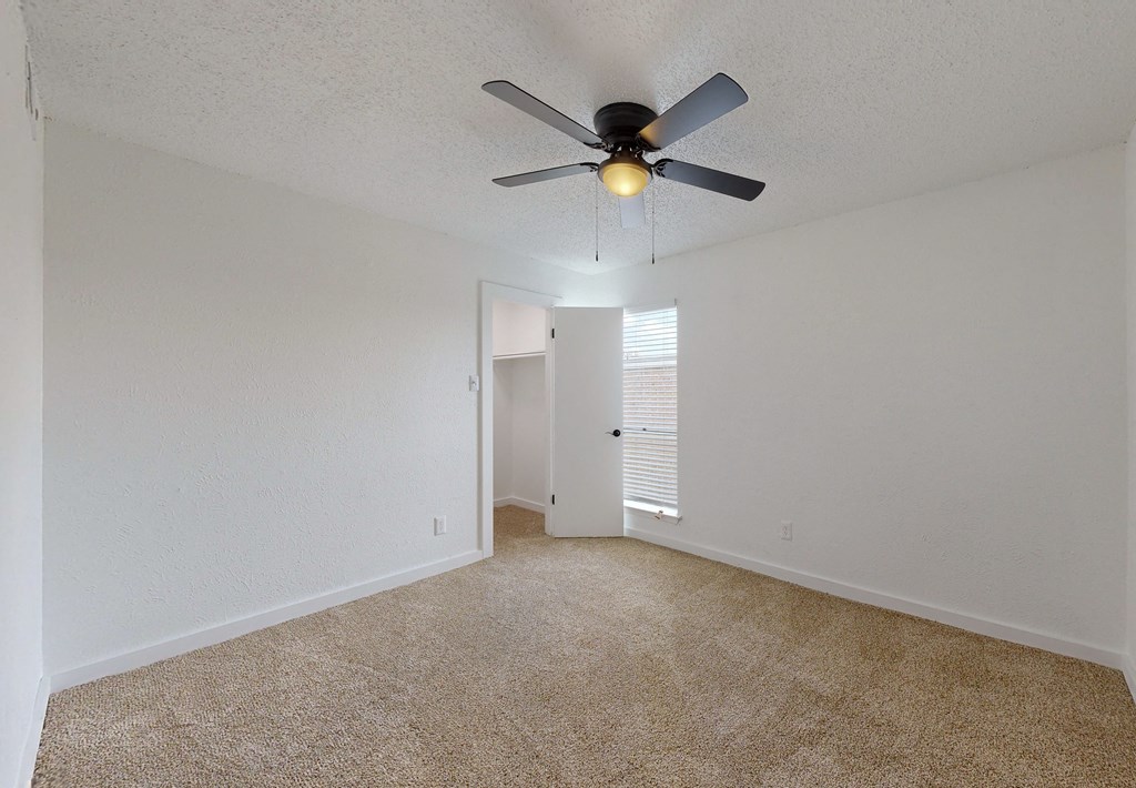 an empty living room with a ceiling fan and a window