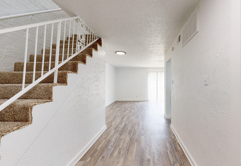 an empty living room with a staircase in a house with white walls