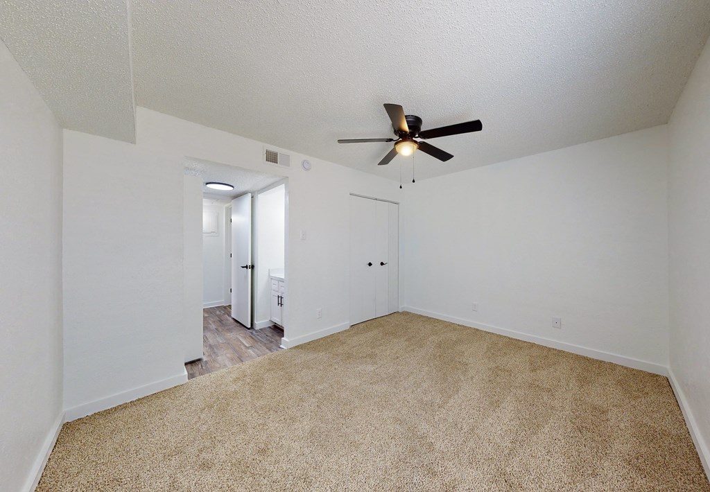 a spacious living room with carpet and a ceiling fan