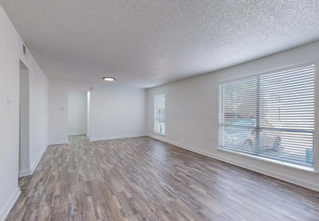 an empty living room with a large window and wood flooring
