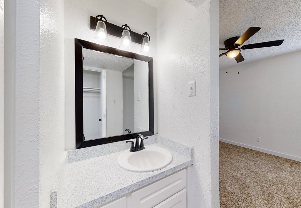 a bathroom with a sink and a mirror and a ceiling fan