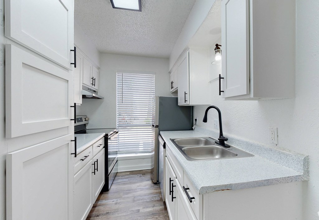 an empty kitchen with white cabinets and a sink