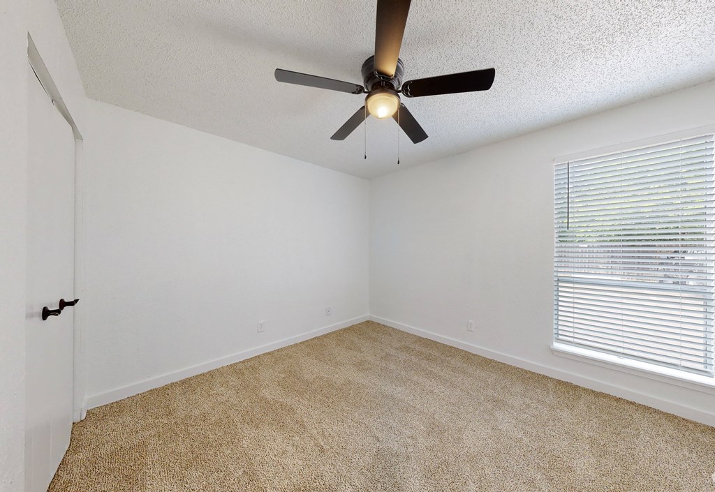 an empty room with a ceiling fan and a window