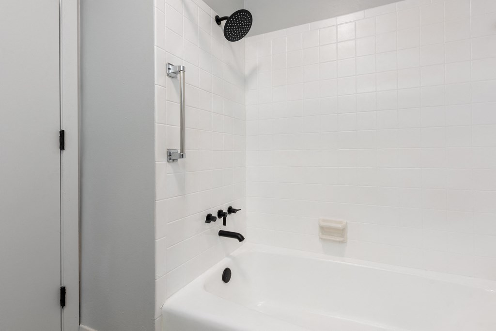 a bathroom with white tiles and a white bathtub