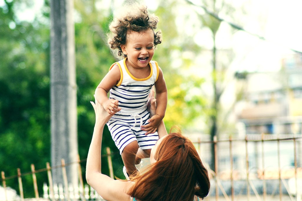 a woman holding a little girl up in the air