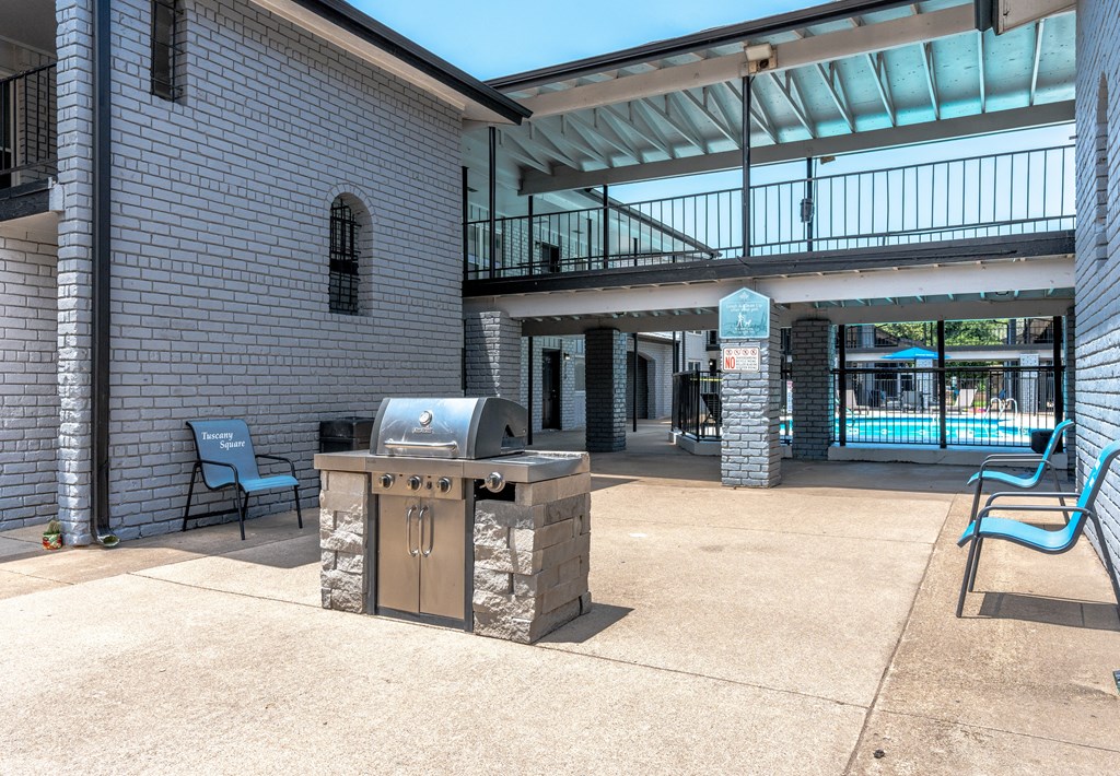 a patio with a grill and a building with a pool