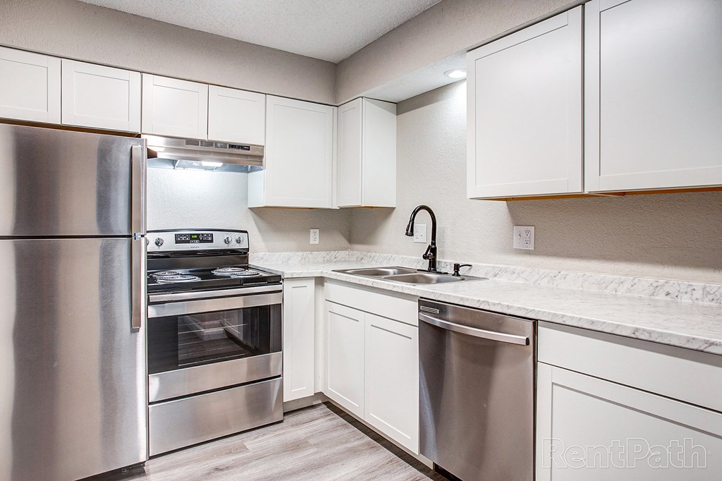 a kitchen with white cabinets and stainless steel appliances