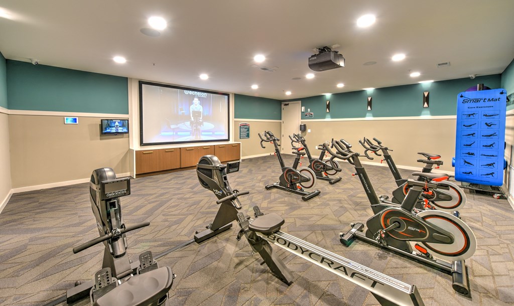 a gym with exercise bikes and a projection screen at Pinnacle Apartments, Jacksonville, FL