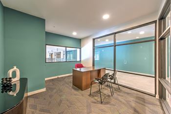 a conference room with large windows and a desk and chairs at Pinnacle Apartments, Jacksonville, FL