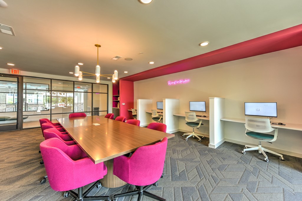 a conference room with a wooden table and pink chairs  at Pinnacle Apartments, Jacksonville, Florida