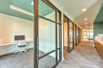 a corridor with a desk and a computer in a room with glass doors at Pinnacle Apartments, Jacksonville, FL
