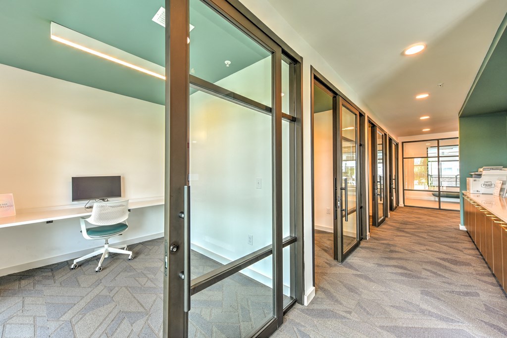 a corridor with a desk and a computer in a room with glass doors at Pinnacle Apartments, Jacksonville