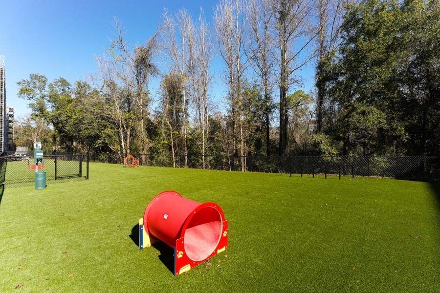a red trash can sitting on top of a lush green field  at Fusion, Jacksonville, FL, 32256