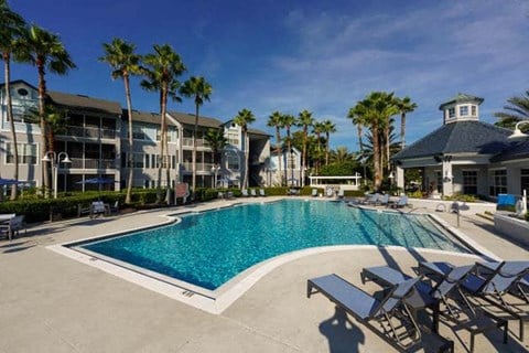 a large pool with chaise lounge chairs and palm trees in the background  at Ocean Park, Jacksonville Beach, Florida