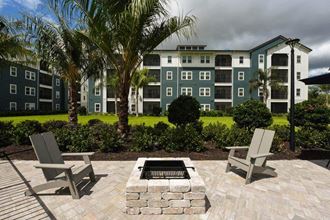 a fire pit with two chairs in front of an apartment building  at Fountainhead, Jacksonville, Florida - Photo Gallery 3