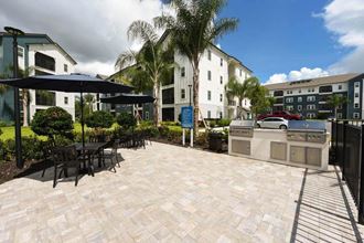 a patio with a grill and tables and umbrellas  at Fountainhead, Florida, 32258