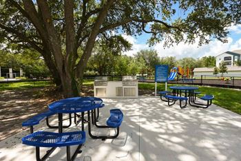 a picnic area with blue tables and chairs and a playground in the background  at Fountainhead, Jacksonville, FL, 32258