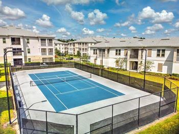 a tennis court with apartments in the background  at Palm Bay Club, Jacksonville, Florida