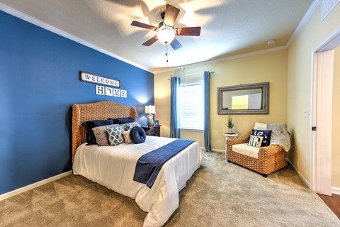 A bedroom with a bed, a chair, and a ceiling fan at Cabana Club - Galleria Club Apartments, Jacksonville, FL