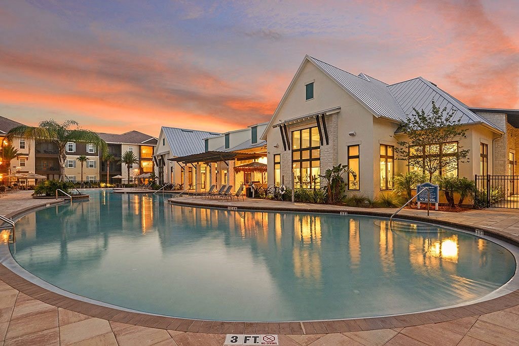 a large swimming pool in front of a house with a sunset in the background  at Cabana Club - Galleria Club, Jacksonville