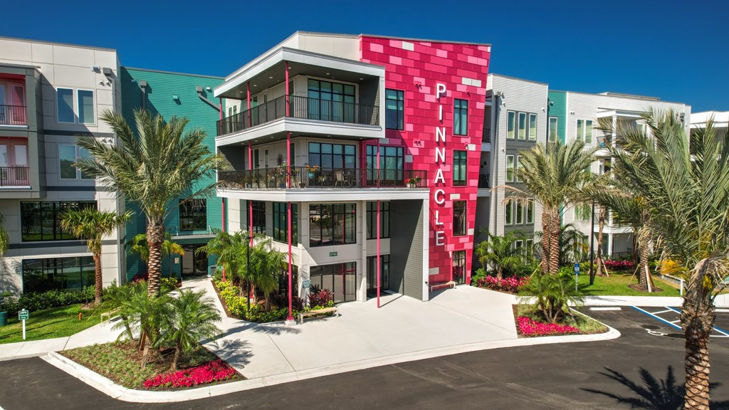a building with a red and white facade and palm trees at Pinnacle Apartments, Jacksonville, FL, 32256
