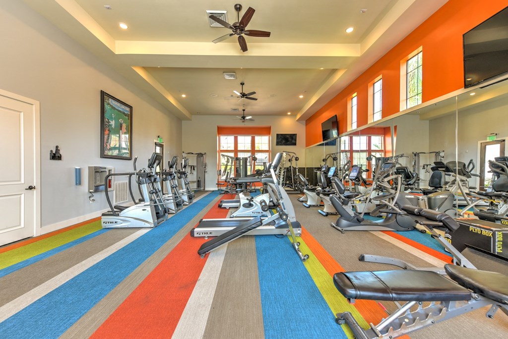 a gym with treadmills and other exercise equipment in a large room with windows at Hacienda Club, Jacksonville