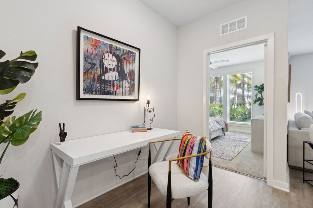 A room with a white desk and a chair with a colorful throw pillow. at Pinnacle Apartments, Jacksonville, 32256