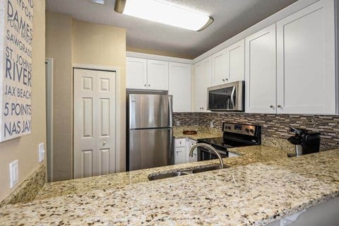 a kitchen with a granite counter top and a stainless steel refrigerator  at Ocean Park, Jacksonville Beach, 32250