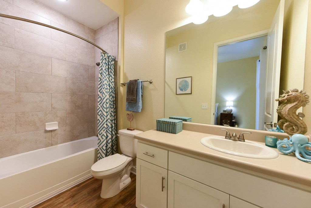 a bathroom with a white sink and toilet next to a bathtub with a shower curtain andat Palm Bay Club, Florida