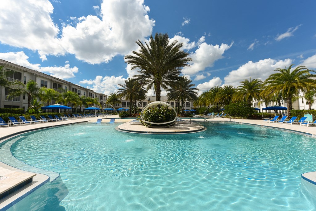a large swimming pool with a fountain and a hotel in the background at Palm Bay Club, Florida, 32258