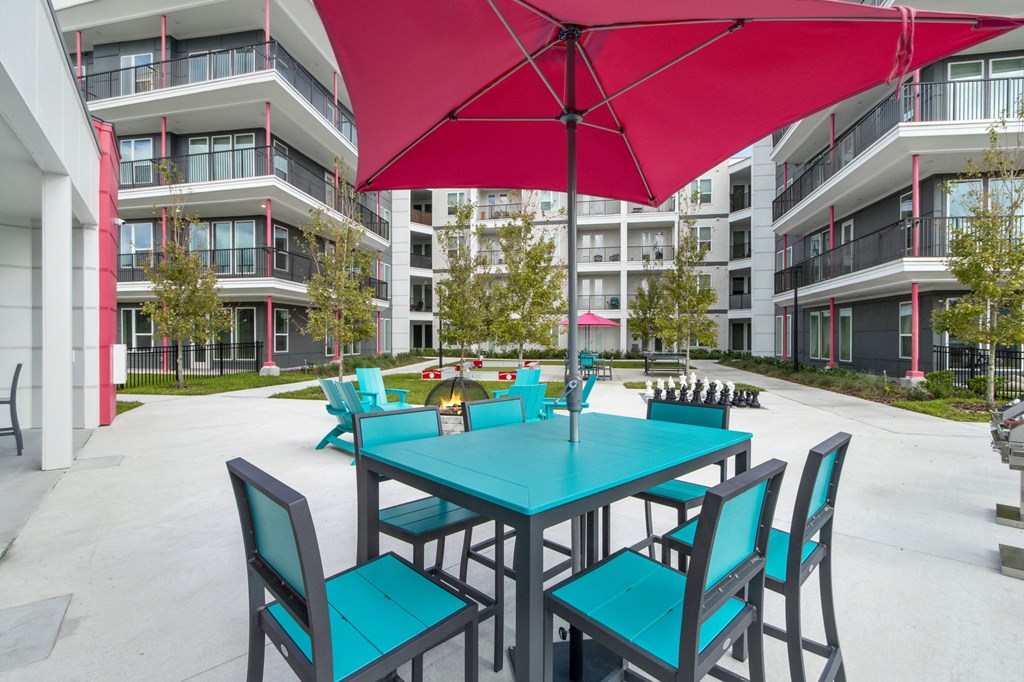A red umbrella shades a table and chairs in a courtyardat Pinnacle Apartments, Jacksonville, FL
