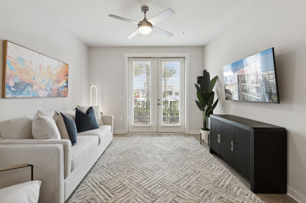 A living room with a couch, a fan, and a painting on the wallat Pinnacle Apartments, Jacksonville, FL