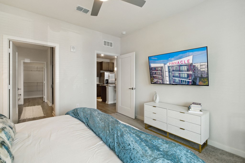 A bedroom with a bed, dresser, and a painting of a building on the wallat Pinnacle Apartments, Jacksonville, FL