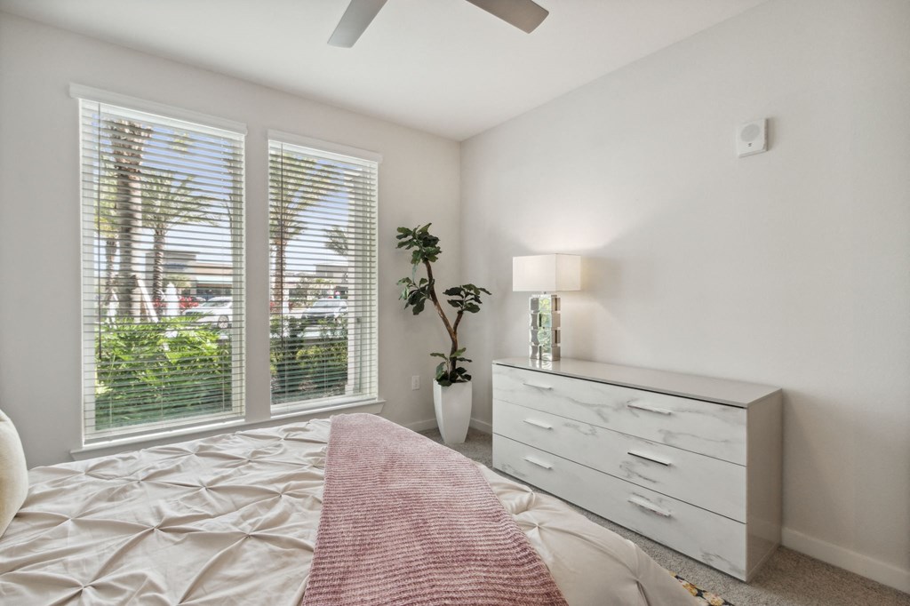 A bedroom with a bed, dresser, and window with blindsat Pinnacle Apartments, Jacksonville, FL
