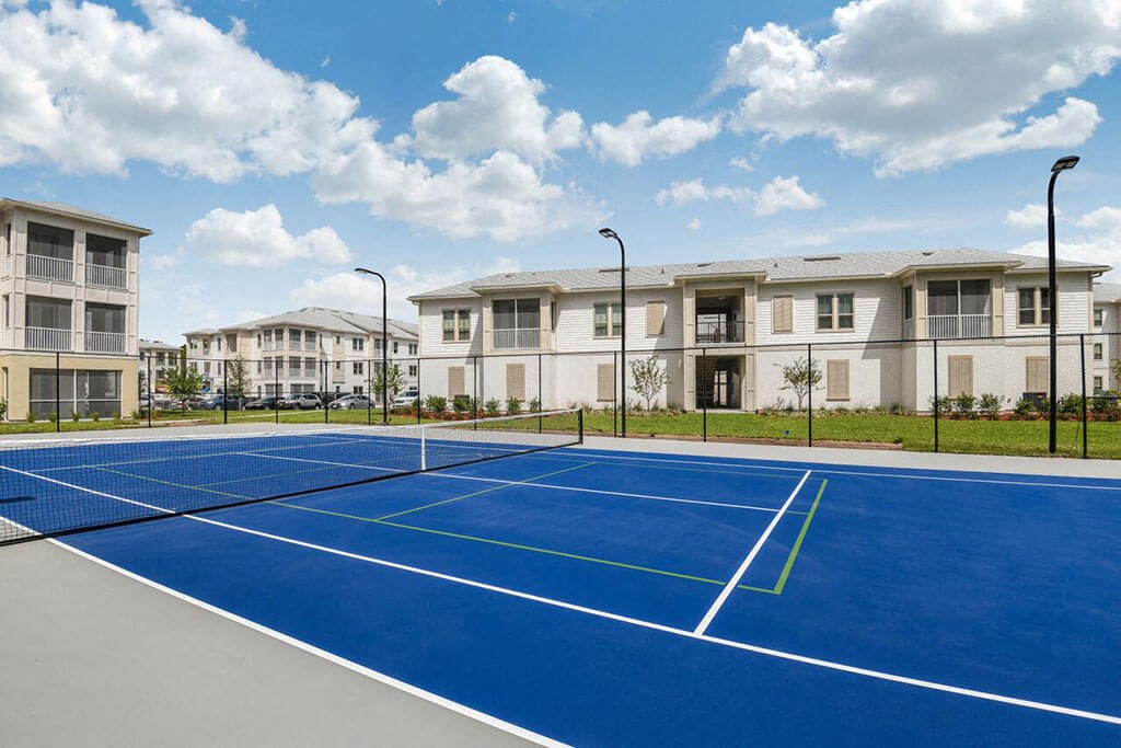 a blue tennis court with apartments in the background  at Palm Bay Club, Jacksonville, 32258