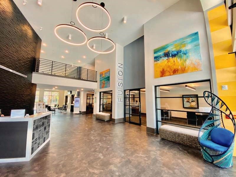 a lobby with a blue chair and a yellow wall  at Fusion, Jacksonville, FL, 32256