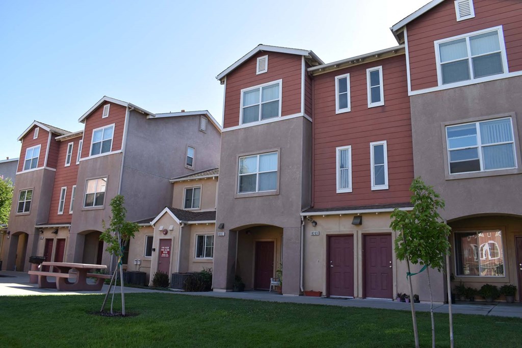 a row of apartments with a lawn and a picnic table
