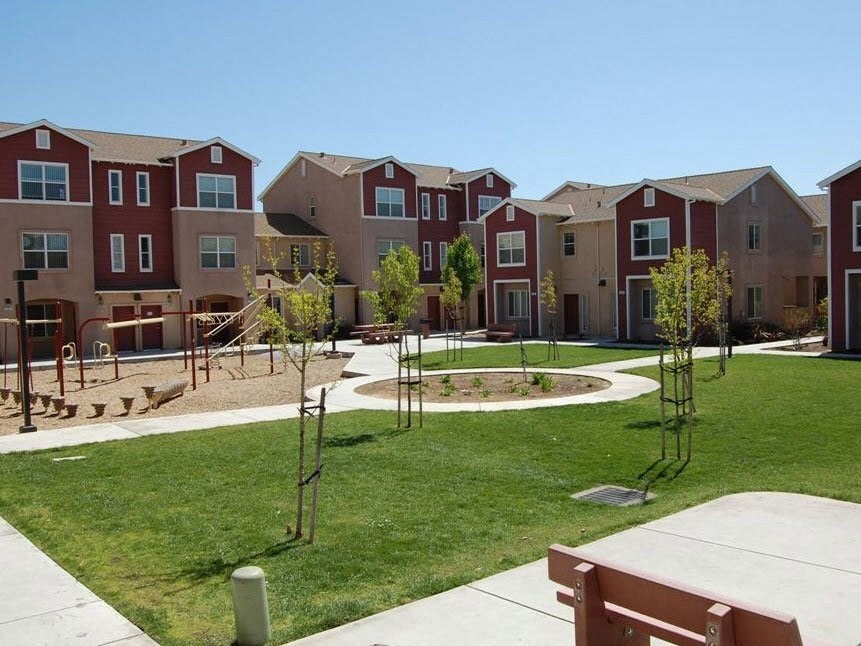 an apartment building with green grass and trees in front of it