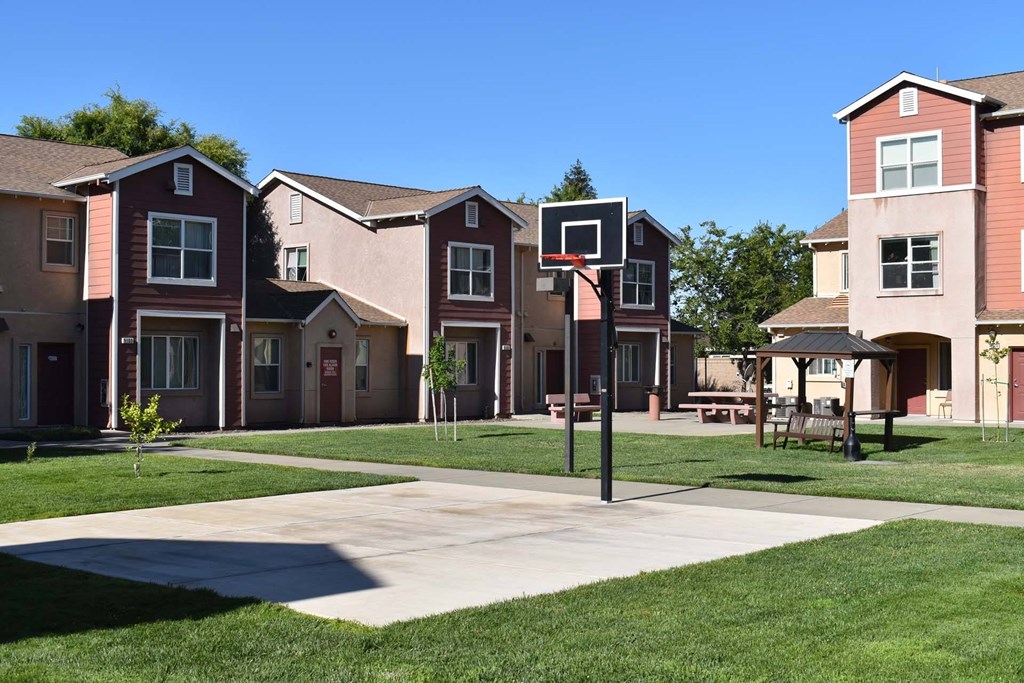 an outdoor basketball court in front of a row of houses